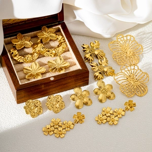 Elegant gold flower earrings collection featuring irregular textures on white silk background
