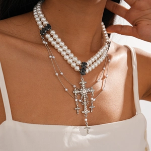 Detail of gothic multi-layer pearl necklace featuring a large rhinestone cross pendant