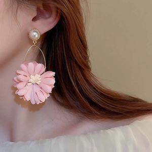 Macro view of oversized pink fabric flower earrings with pearl details on a model