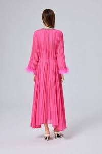 Détail d'une robe plissée fuchsia montrant le dos et les poignets en plumes d'autruche