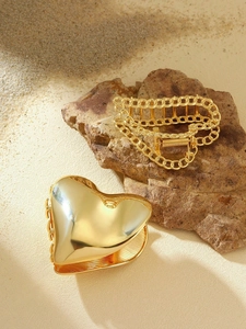 Detail of gold metal heart hair claw and chain clip on natural stone background