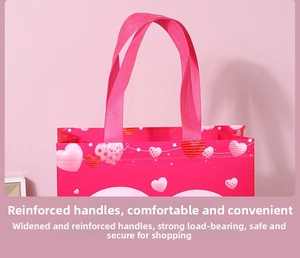 Detail of pink non-woven gift bag showing reinforced handles and heart pattern print