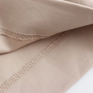 Gros plan d'un tissu tissé beige montrant des coutures et des détails de surjet précis