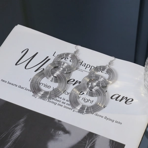 Detail of silver geometric multi-layer concentric circle drop earrings on a fashion magazine
