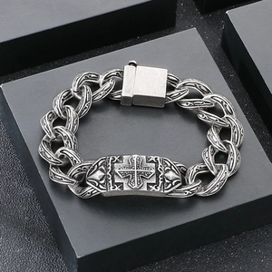 Close-up of vintage silver cross relief and engraved links on a punk style steel bracelet