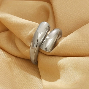 Close-up of a silver-tone streamlined wrap ring nestled in champagne gold satin fabric