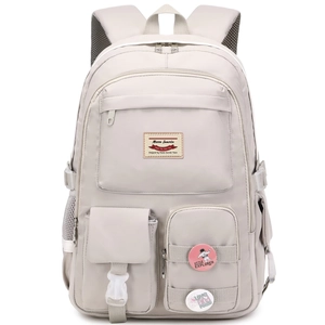 Detail of light grey multi-pocket backpack with leather logo and decorative pins