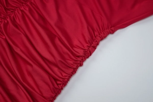 Détail macro du tissu rouge avec une texture froncée élégante et des plis élastiques