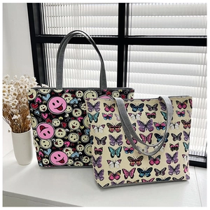Detail view of two canvas tote bags with smile and butterfly prints on a white surface