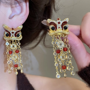 Détail de boucles d'oreilles lion avec pompons rouges et breloques de pièces anciennes
