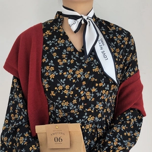Detail of vintage silk scarf tied with burgundy cardigan and floral dress