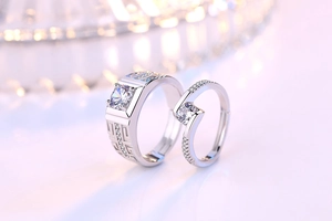 Close-up of geometric pattern couple rings with sparkling zircon inlay and silver finish
