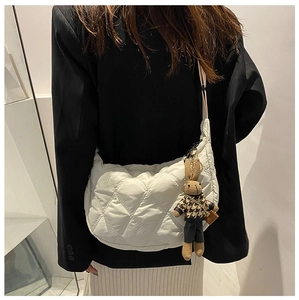 Detail of white quilted dumpling bag with cute rabbit pendant and adjustable strap