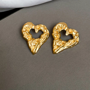 Detailed close-up of golden heart earrings with irregular liquid metal texture finish