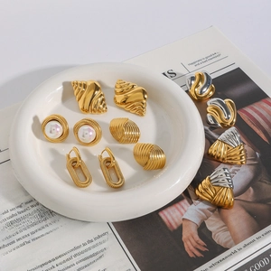 Vintage gold and pearl earring set with shell texture and metallic twists on white plate