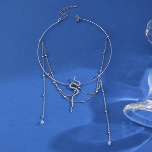 Detailopname van zilveren slang chocker met kristallen kwastjes op blauwe achtergrond