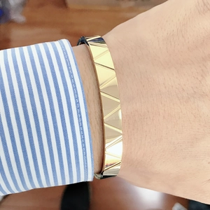 Close-up of gold stainless steel Roman numeral bracelet worn with a striped shirt