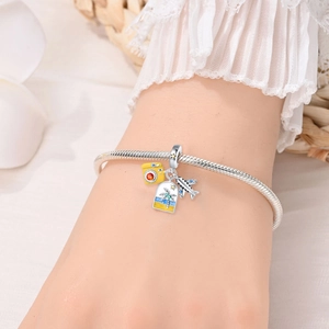 Detailed shot of silver charm bracelet with travel camera and airplane pendants on wrist