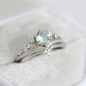 Macro shot of silver crown stacking rings with light blue zircon and wave band detail