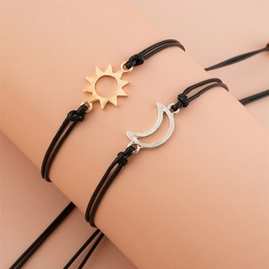 Detail of hand-woven sun and moon charm bracelets on wrist with black wax cord