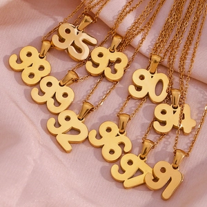 Collection of gold 18K plated stainless steel birth year number necklaces on pink silk