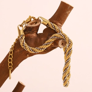 Détail d'un bracelet chaîne torsadé bicolore en acier inoxydable sur bois naturel