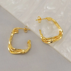 Golden multi-layer geometric square earrings with a twisted metallic texture on grey fabric
