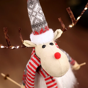 Close-up of plush Christmas reindeer with LED lights on antlers and festive scarf