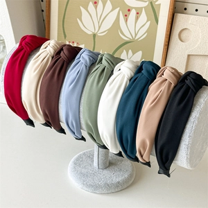 Close-up of wide knotted fabric headbands in multiple colors on a display stand