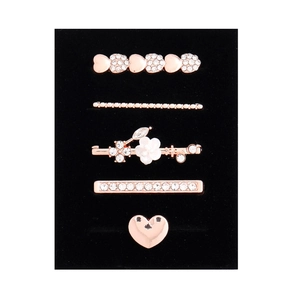 Detailed view of 5-piece rose gold rhinestone hair clip set on black velvet card