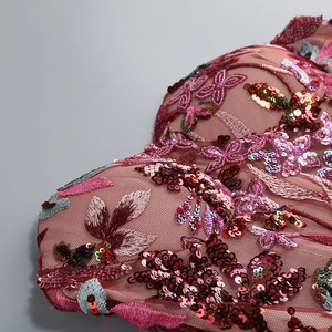 Detailed macro shot of intricate sequins and floral embroidery on wine red mesh dress