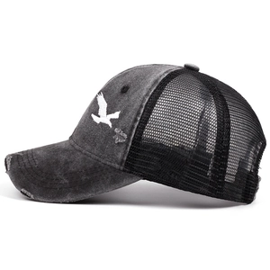 Distressed vintage trucker hat with white bird embroidery and black mesh back.