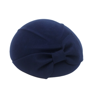 Detail of navy blue wool beret with large decorative bow on a white background