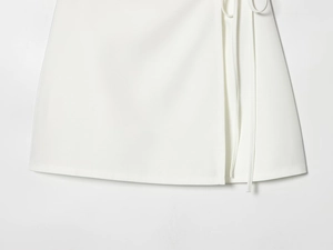 Detailed close-up of white A-line skirt with side tie knot and crisp textured fabric