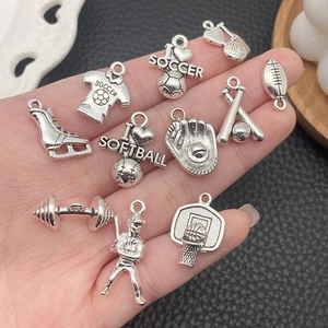Silver sports-themed alloy charms for DIY jewelry held in hand over black leather background