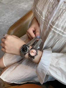 Detail of silver stainless steel watch bands with pink and black dials and calendars