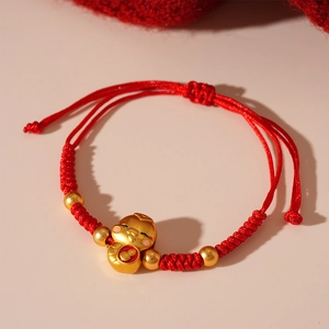 Detailed macro view of woven red string bracelet with gold lucky charm and beads