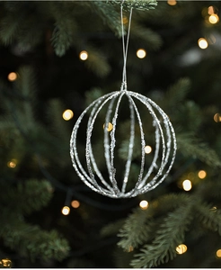 Silver glittered exploding star Christmas ball ornament hanging on a festive tree branch