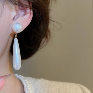 Close-up of elegant silver needle drop earrings with white pearls on a model