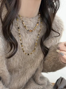 Gros plan d'un collier à double couche avec pierres œil de tigre sur un pull marron