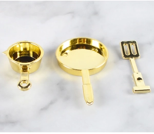 Detailed view of polished gold miniature cookware set including a pan, pot, and spatula