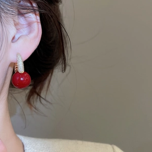Close-up of elegant red zircon drop earrings with gold pavé crystal ear hooks on a model