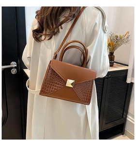 Close-up of brown crocodile pattern handbag with elegant gold square metal buckle