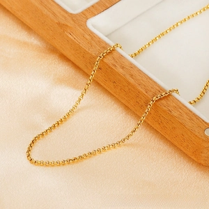 Detail of 18K gold plated stainless steel rolo chain necklace on a luxury wood tray