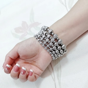 Close-up of stacked silver stainless steel beaded bracelets with mixed textures on wrist