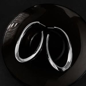 Minimalist silver oval hoop earrings for women on a sleek black decorative plate