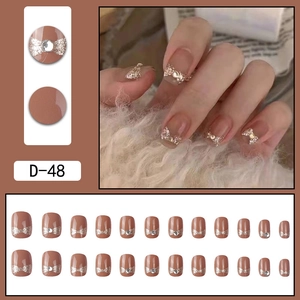 Short nude press-on nails with glitter bow and rhinestone accents for women