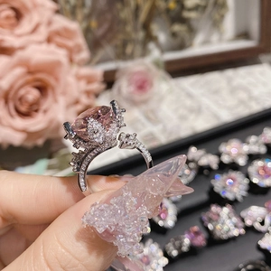 Macro shot of 18K plated bow ring with large pink heart-shaped stone and side diamonds