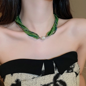 Detail of green beaded crystal necklace with twisted weave and sparkling clasp on model