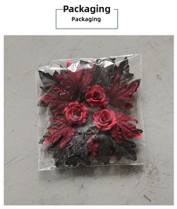 Macro detail of artificial red roses and dark maple leaves in clear plastic packaging